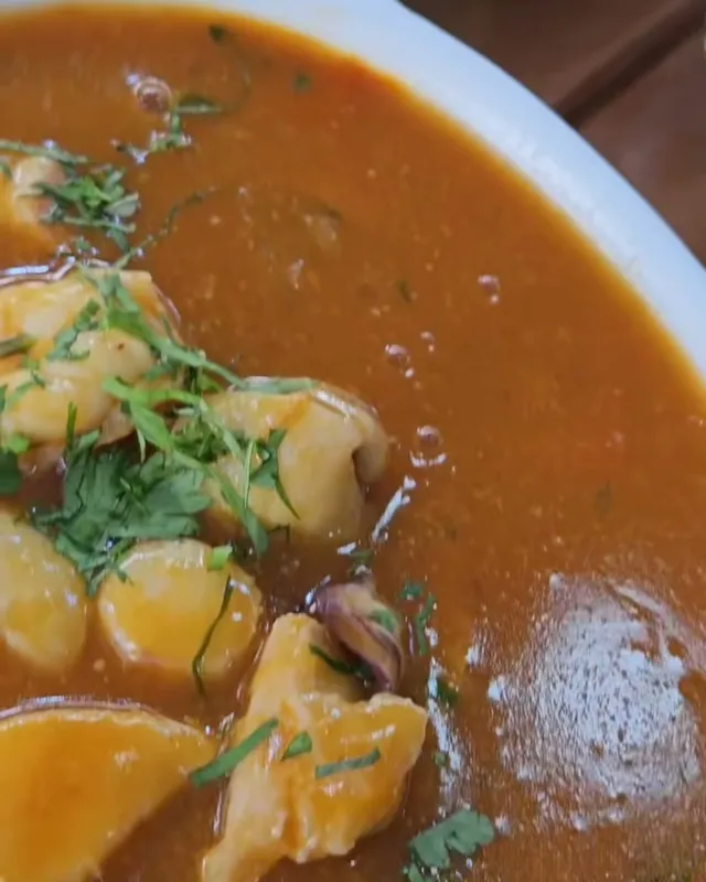 Un plato hondo con pescado y mariscos en su jugo